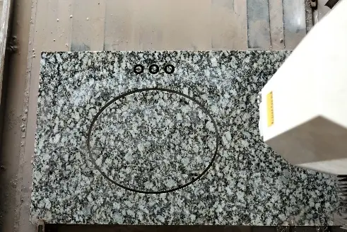 CNC machine cutting a sink and faucet holes into a granite vanity top